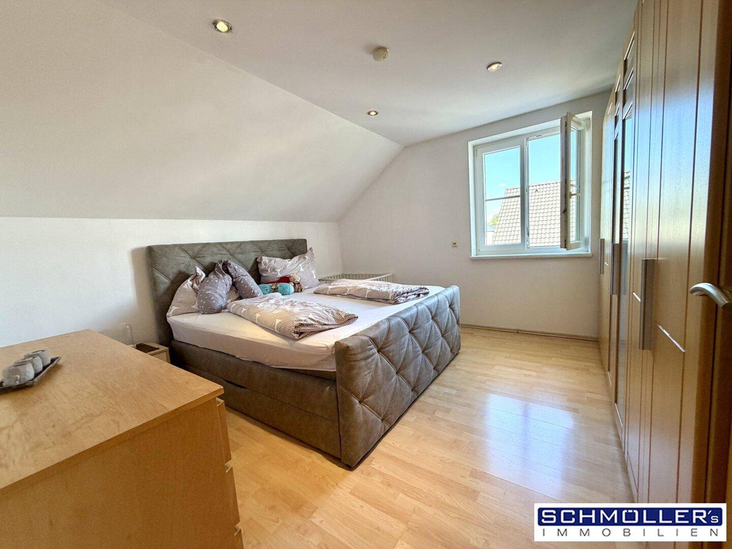 Gemütliches Schlafzimmer mit Dachschräge, Holzboden und Einbauschränken.