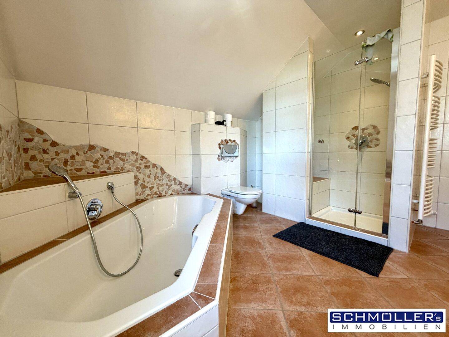Geräumiges Badezimmer mit Eckbadewanne, Dusche und gefliesten Wänden in warmen Farbtönen.