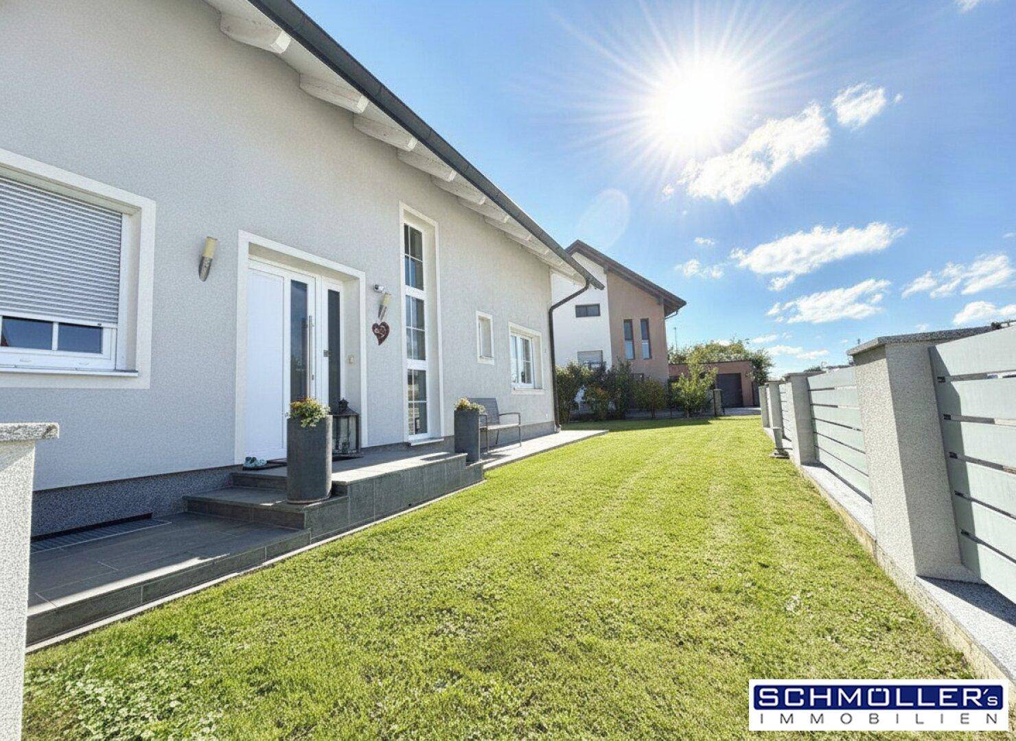 Eingangsbereich des Hauses mit gepflegtem Vorgarten und sonniger Rasenfläche.