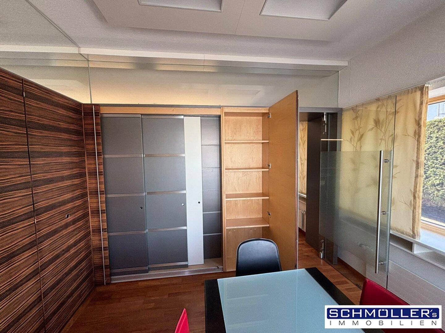 Büroraum mit integrierten Schränken, teilweise mit Milchglastüren, und einer eleganten Holzwandverkleidung.