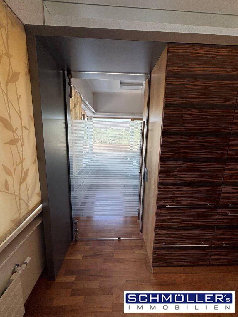 Flur oder Übergangsbereich mit Holzboden, Holzverkleidung und einer Milchglas-Schiebetür.