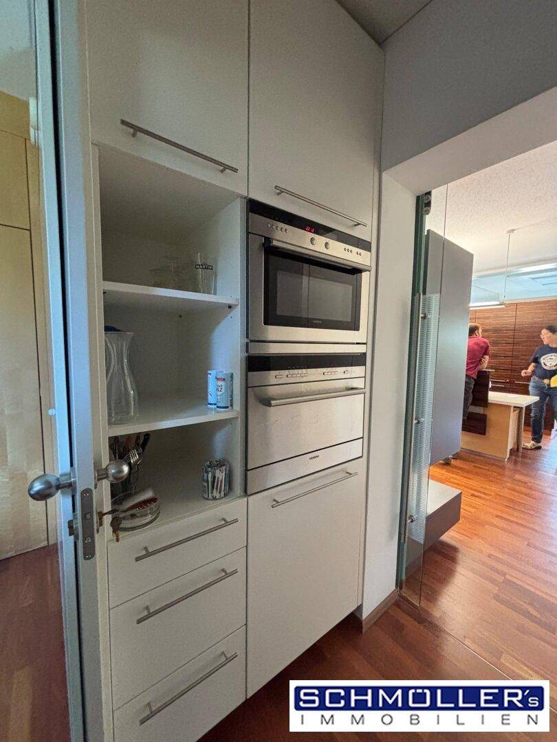 Integrierte Küchenzeile mit Mikrowelle, Backofen und offenen Regalen in einem modernen Design.