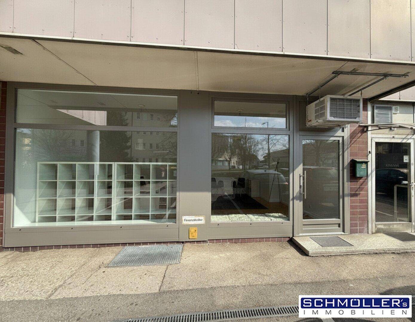 Breite Ansicht der Geschäftsfassade mit großen Schaufenstern, Eingang und einer Klimaanlage über der Tür.