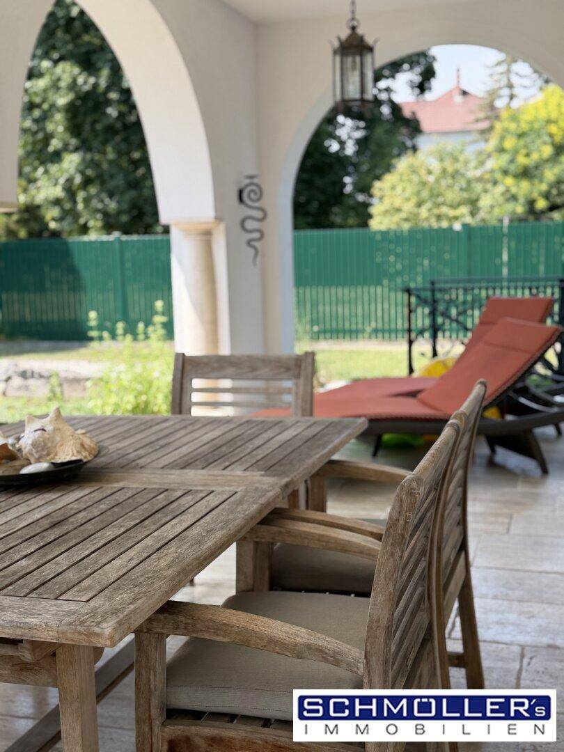 Gemütlicher Essbereich im Freien auf der überdachten Loggia mit Blick in den Garten.