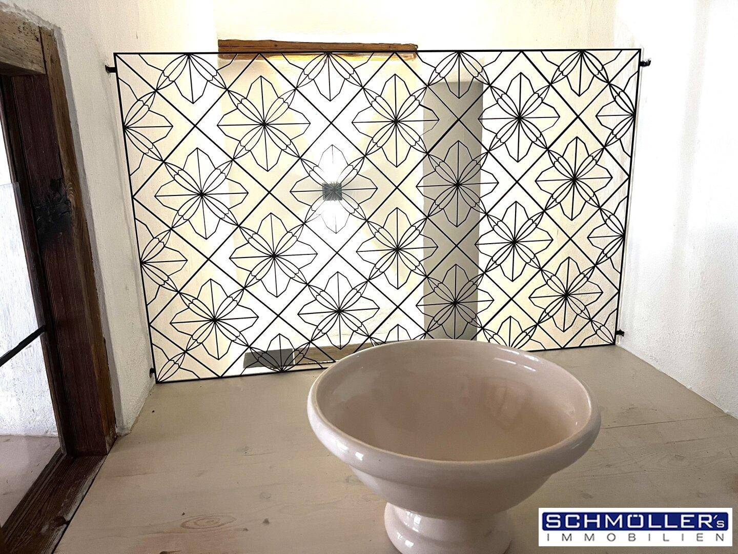 WC-Bereich mit stilvollem Trenngitter, hellem Holz und Keramikwaschbecken.