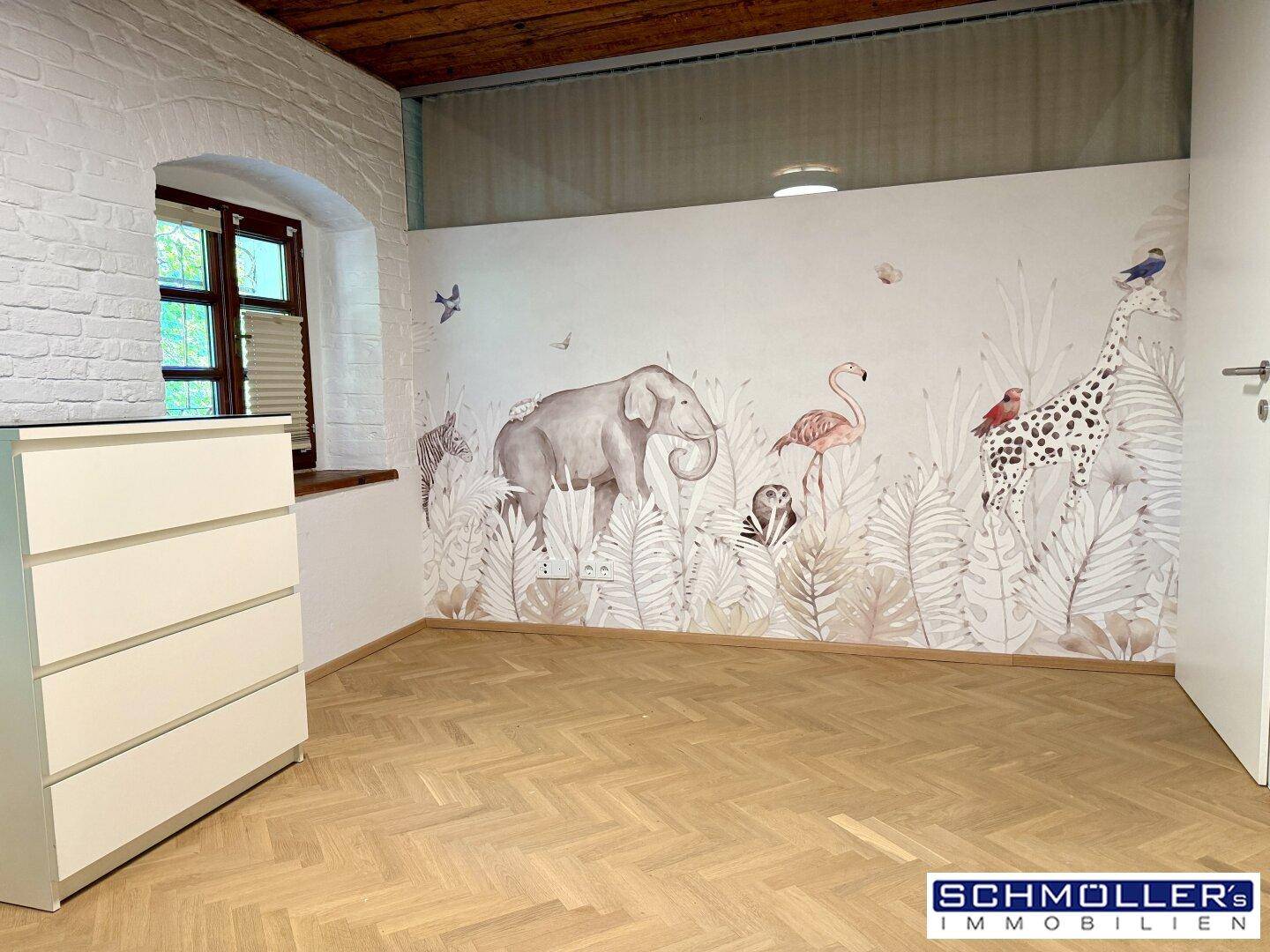 Helles Kinderzimmer mit verspielter Tiermotiv-Tapete, Fischgrätparkett und freiliegenden Holzdeckenbalken.