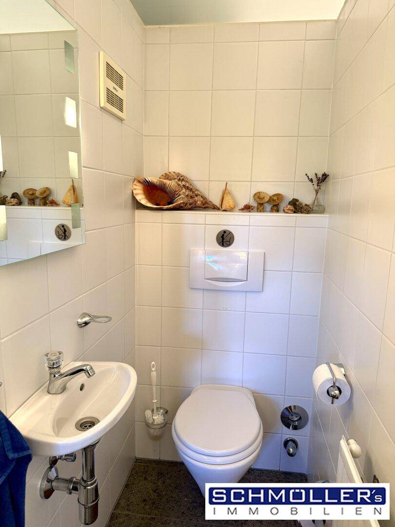 Kleines Gäste-WC mit Wand-WC, Waschbecken und weißen Fliesen.