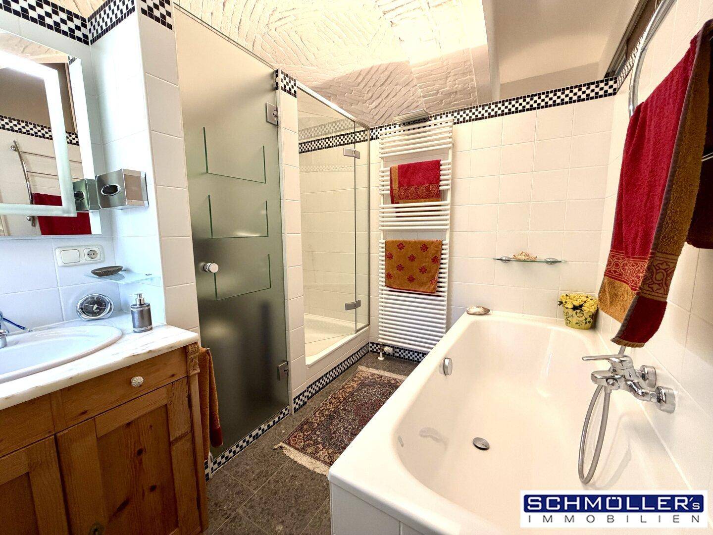 Helles Badezimmer mit Badewanne, Duschkabine und beheiztem Handtuchhalter.