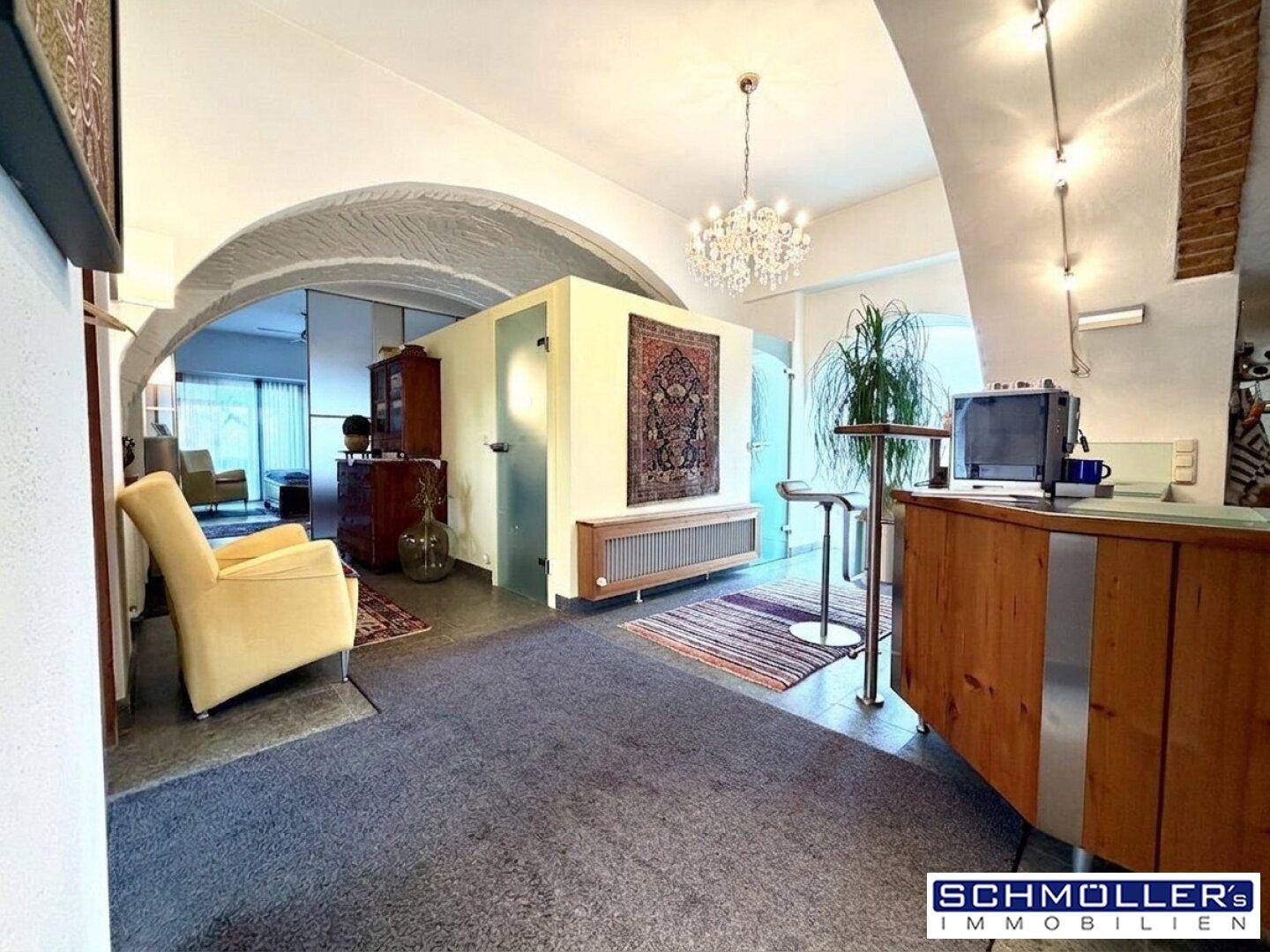 Geräumiger Eingangsbereich mit gewölbten Decken, Teppichboden und Blick in den Wohnbereich.