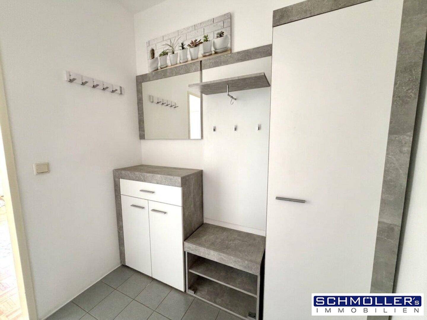 Eingangsbereich mit Garderobe, Spiegel und Fliesenboden.