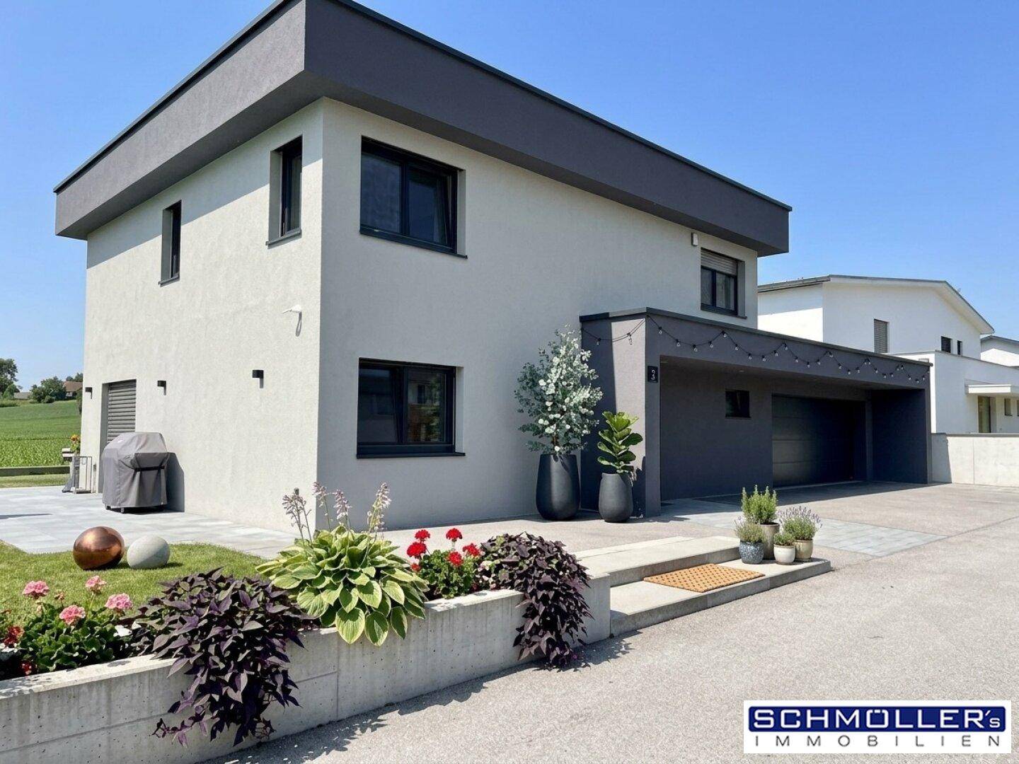 Modernes Einfamilienhaus mit gepflegtem Vorgarten, Carport und Flachdacharchitektur.