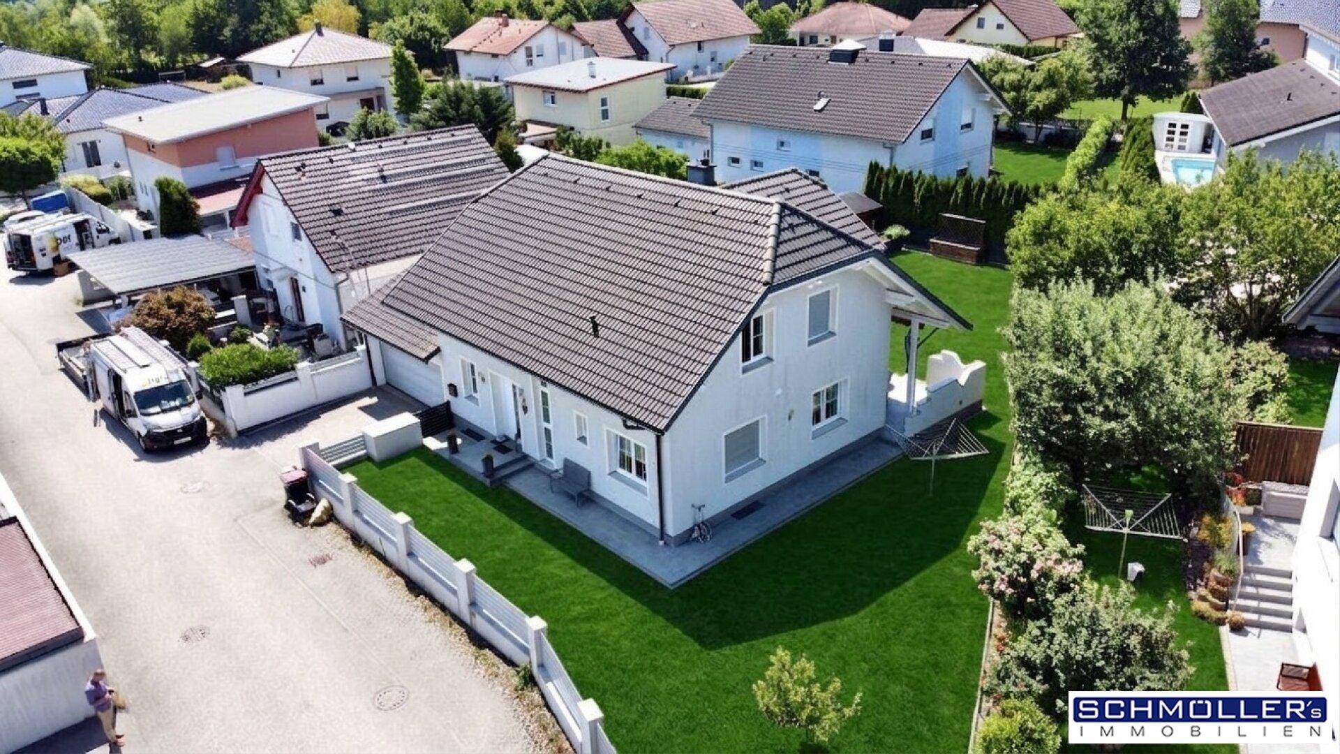 Luftaufnahme eines Einfamilienhauses mit gepflegtem Garten und angrenzender Wohnsiedlung.