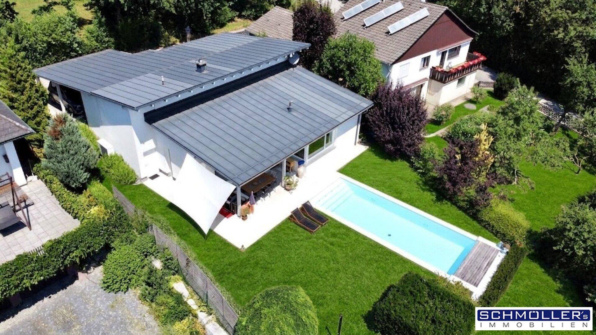 Luftaufnahme einer modernen Wohnanlage mit Pool, weitläufigem Rasen und schattiger Terrasse.