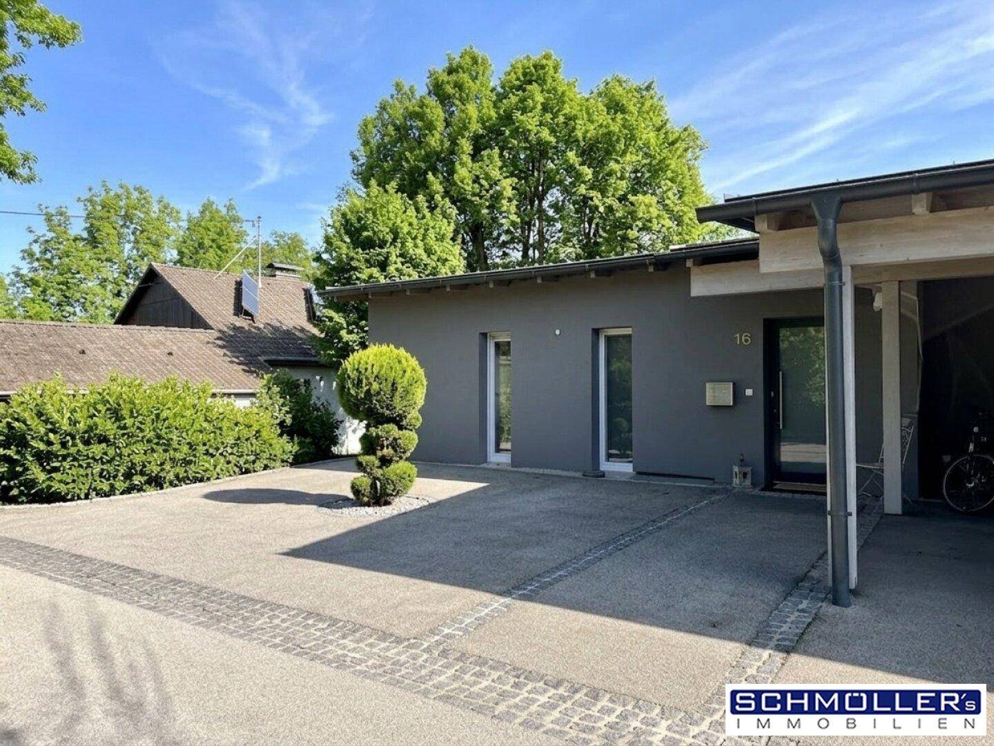 Eingangsbereich eines modernen Hauses mit gepflasterter Auffahrt und Carport.