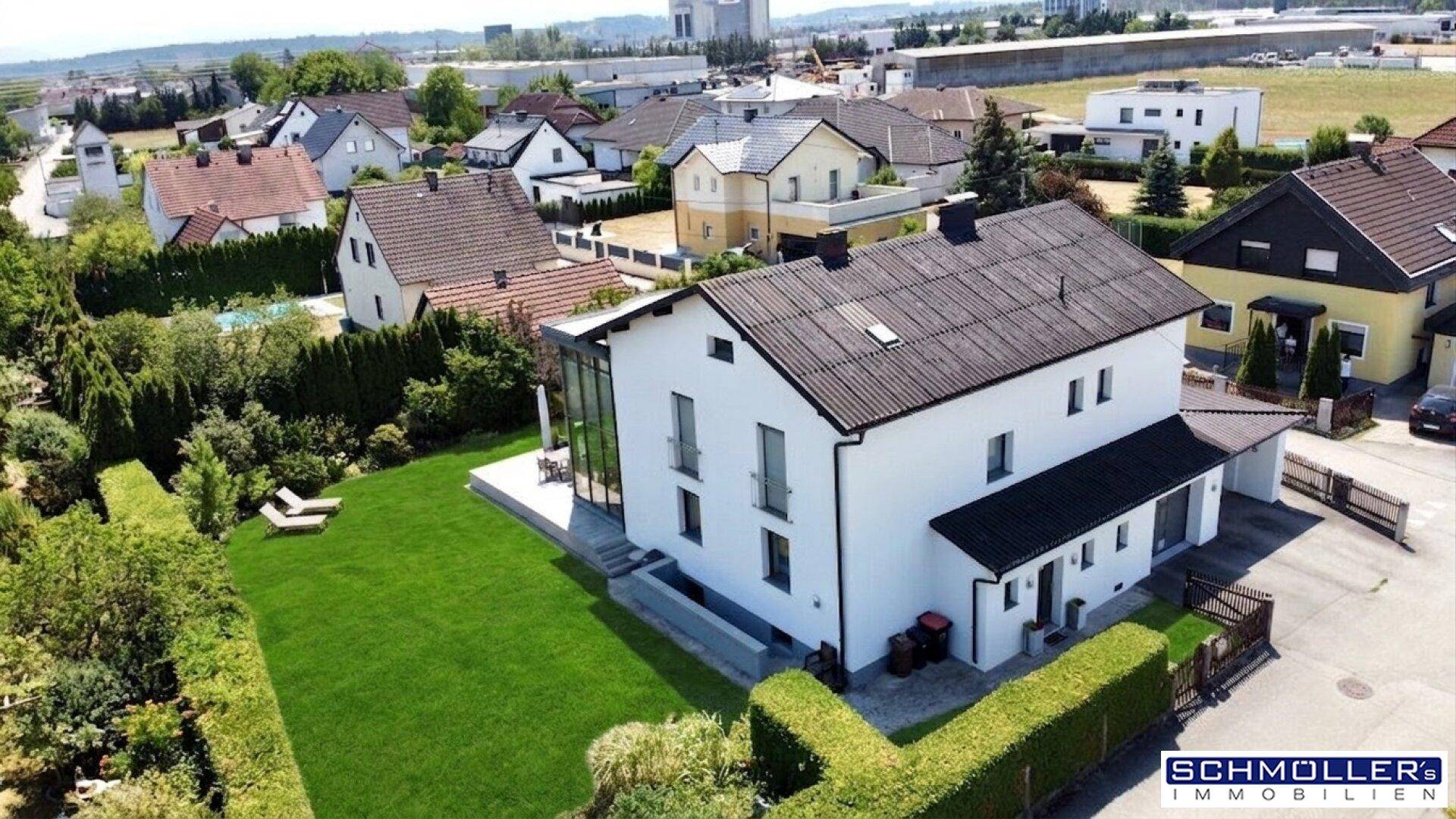 Seitenansicht des Hauses mit gepflegtem Garten, hohen Hecken und Blick auf die Nachbarschaft.