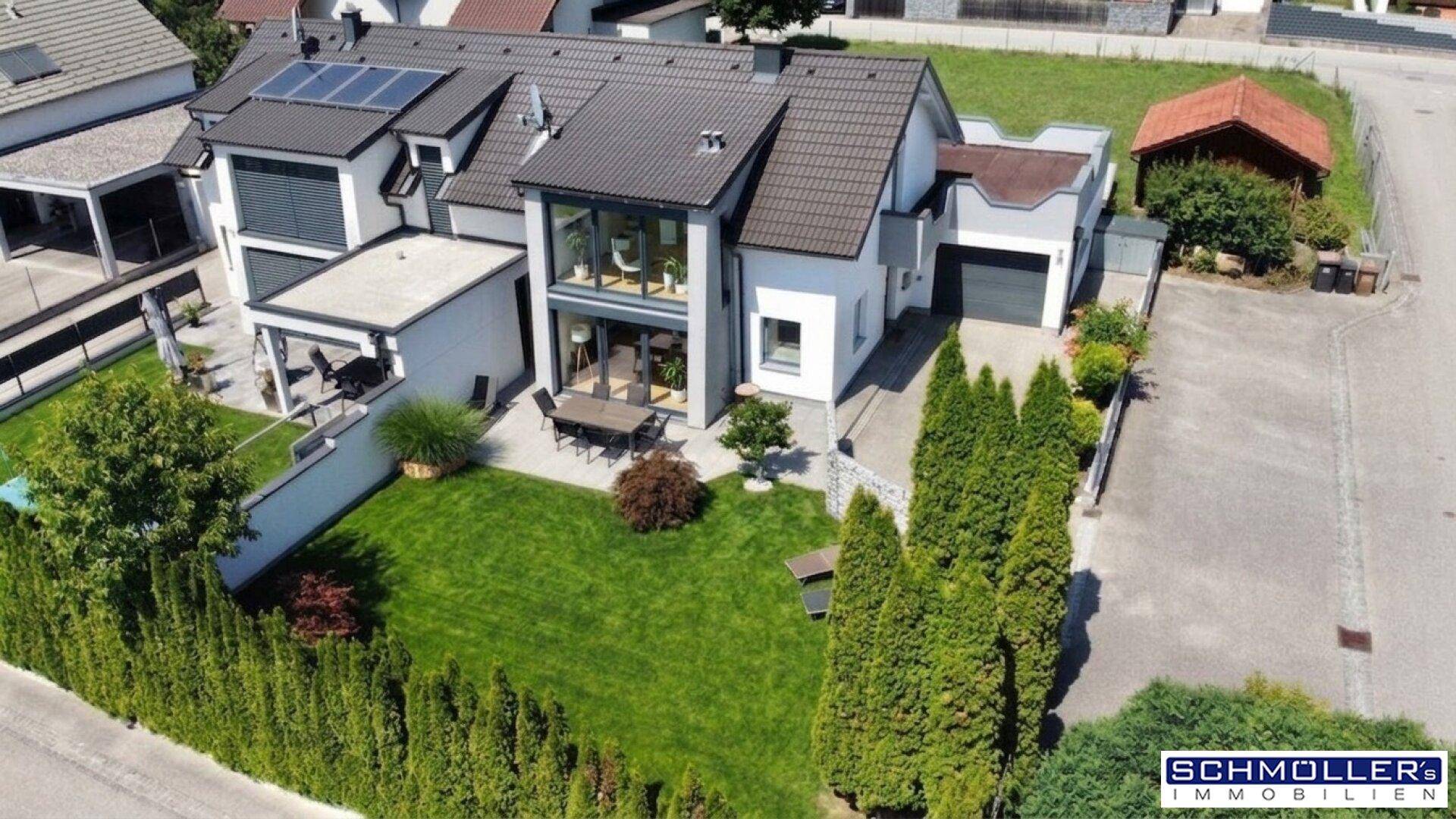 Moderne Villa mit gepflegtem Garten, großer Terrasse und Photovoltaikanlage auf dem Dach.
