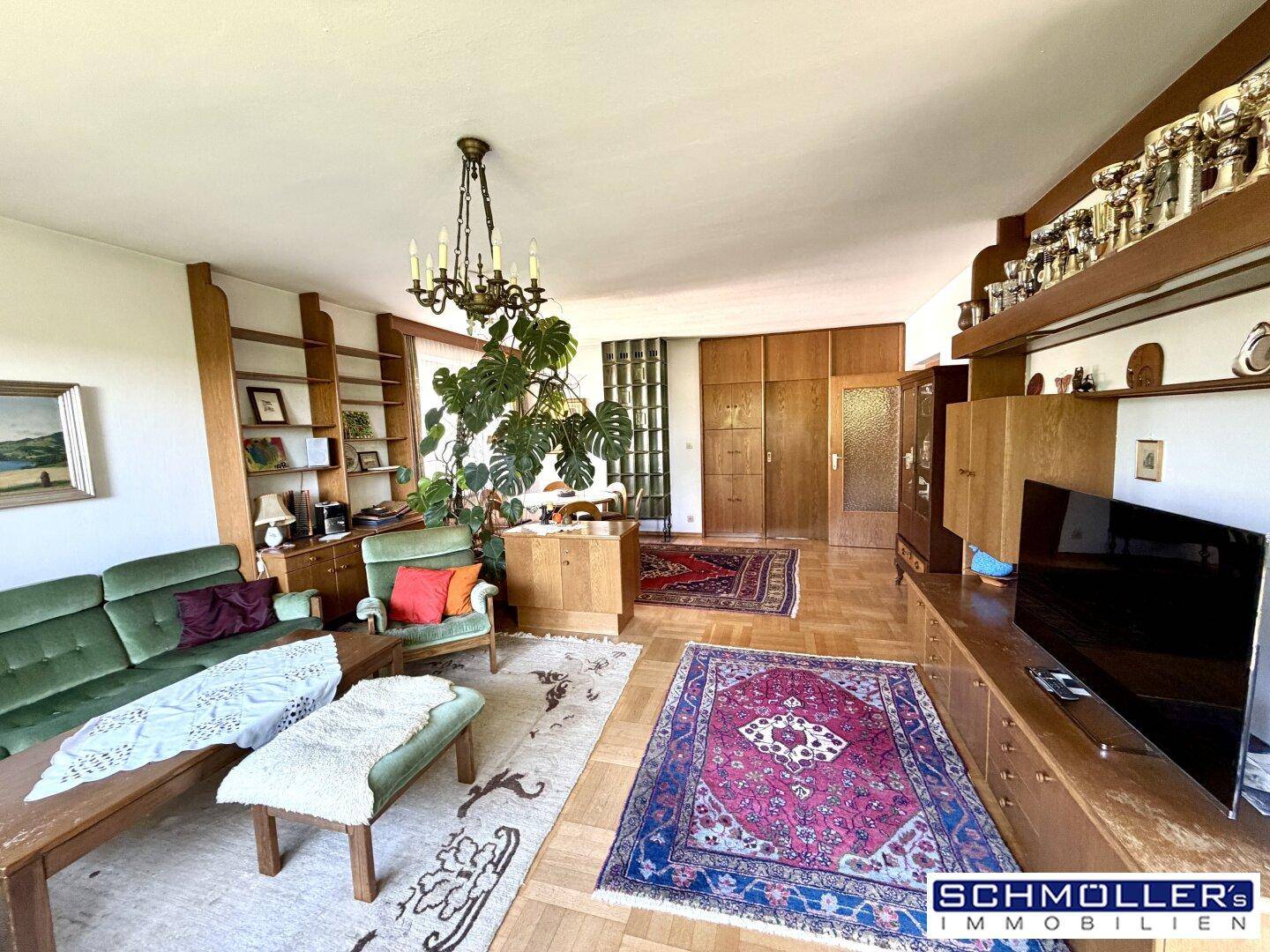 Großzügiges Wohnzimmer mit traditionellen Möbeln, Holzboden und einem Kronleuchter.