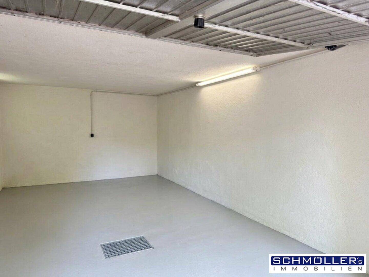 Leere Garage mit weiß gestrichenen Wänden und einem einfachen Betonboden.