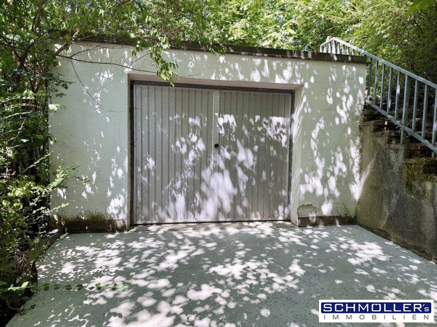 Einzelgarage mit weiß gestrichener Fassade und einem einfachen Garagentor.