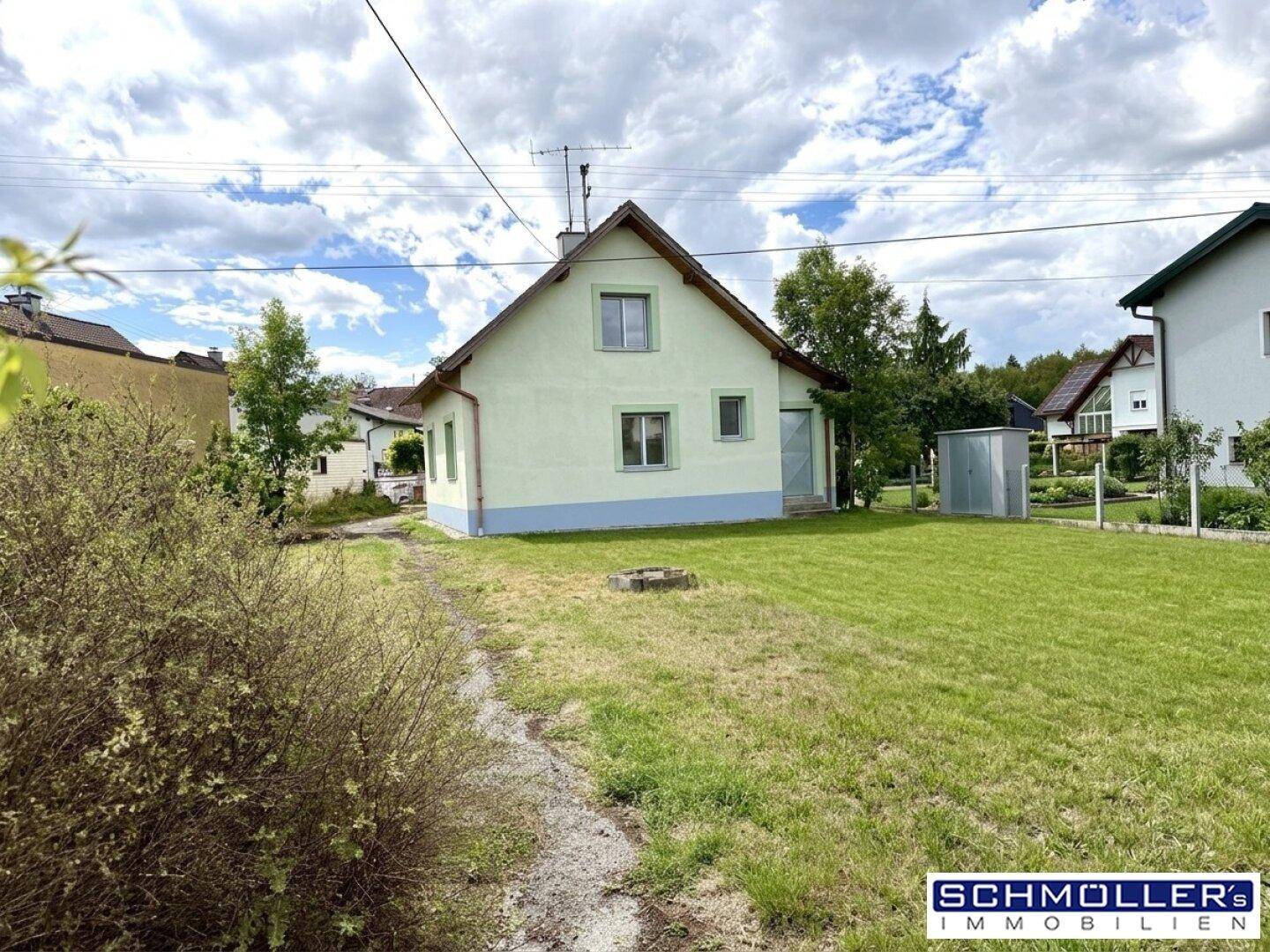 Rückansicht des Einfamilienhauses mit gepflegtem Rasen und einem kleinen Geräteschuppen im Garten.