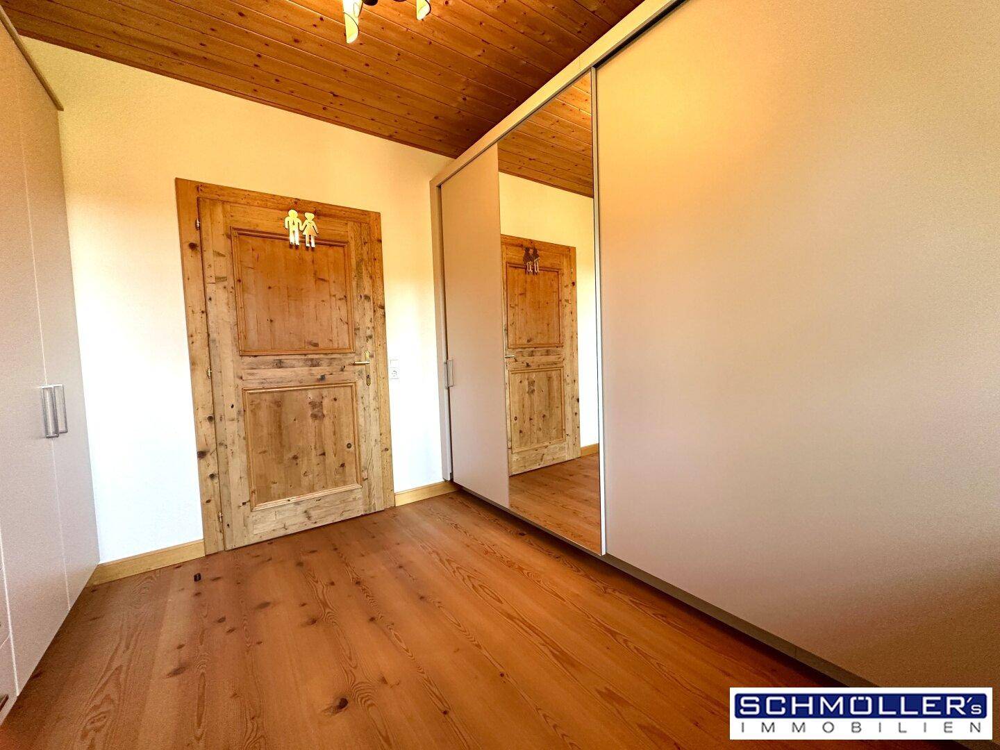 Flur mit rustikalen Holztüren, Holzboden und Holzdecke sowie praktischen Einbauschränken.