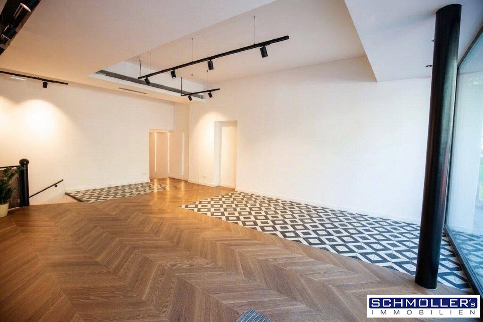 Geräumiger, leerer Geschäftsraum mit Fischgrätparkett und gemusterten Fliesen, bereit zur Einrichtung.