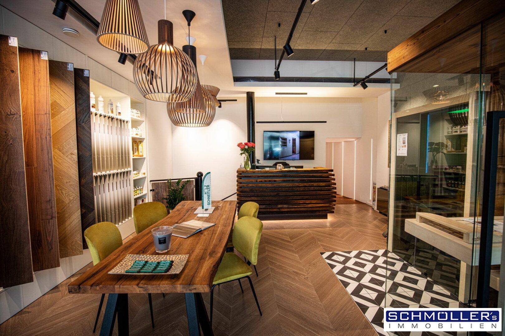 Stilvoller Geschäftsraum mit Holztisch, modernen Lampen und einer Rezeption, perfekt für Kundenempfang.