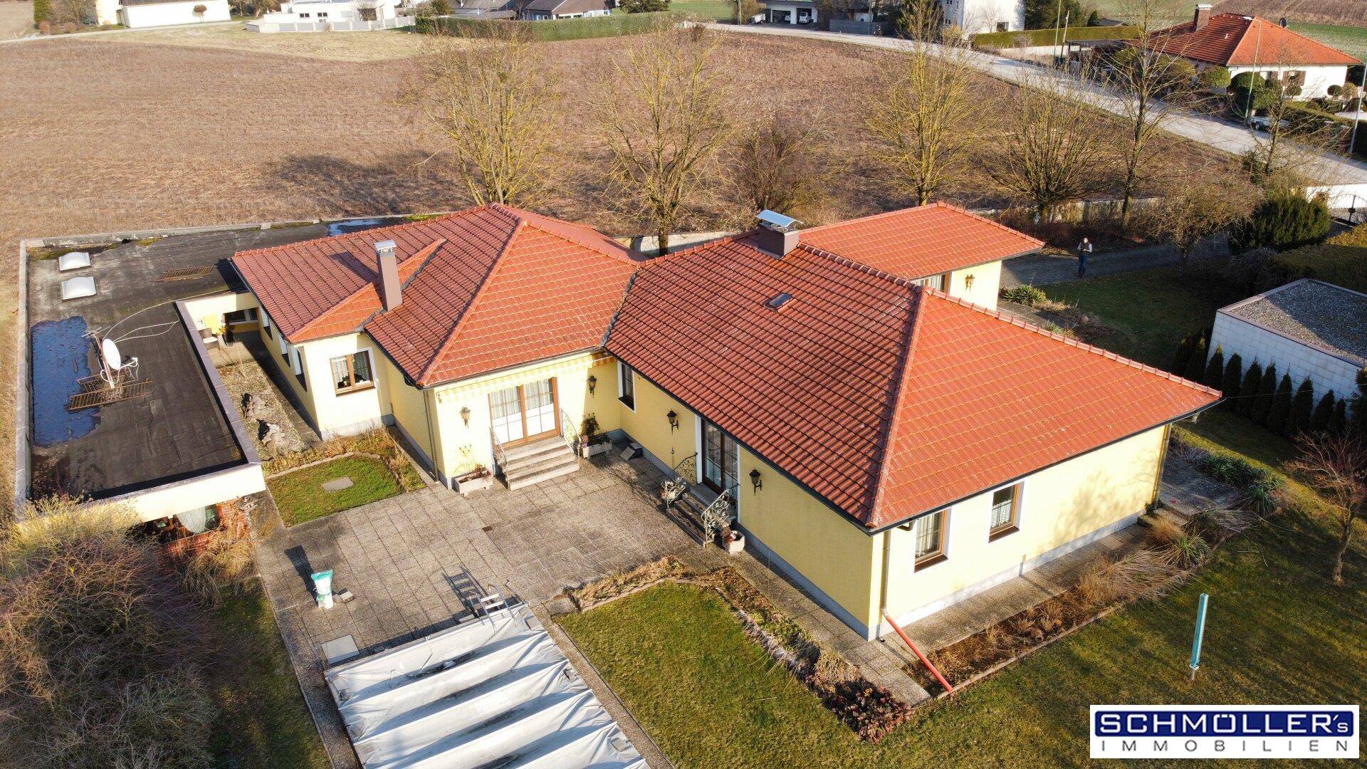 Luftaufnahme des Einfamilienhauses mit großem Garten, Terrasse und überdachtem Poolbereich.