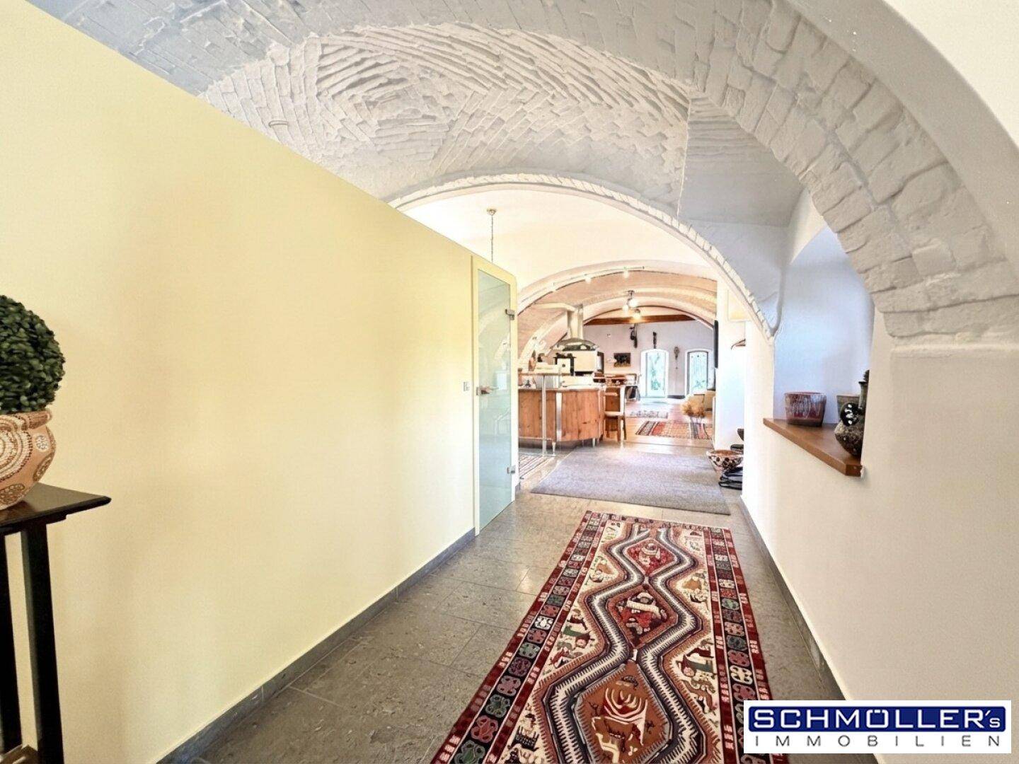 Heller Flur mit Steinboden und beeindruckenden Gewölbedecken, der den Blick in den offenen Wohnbereich freigibt.