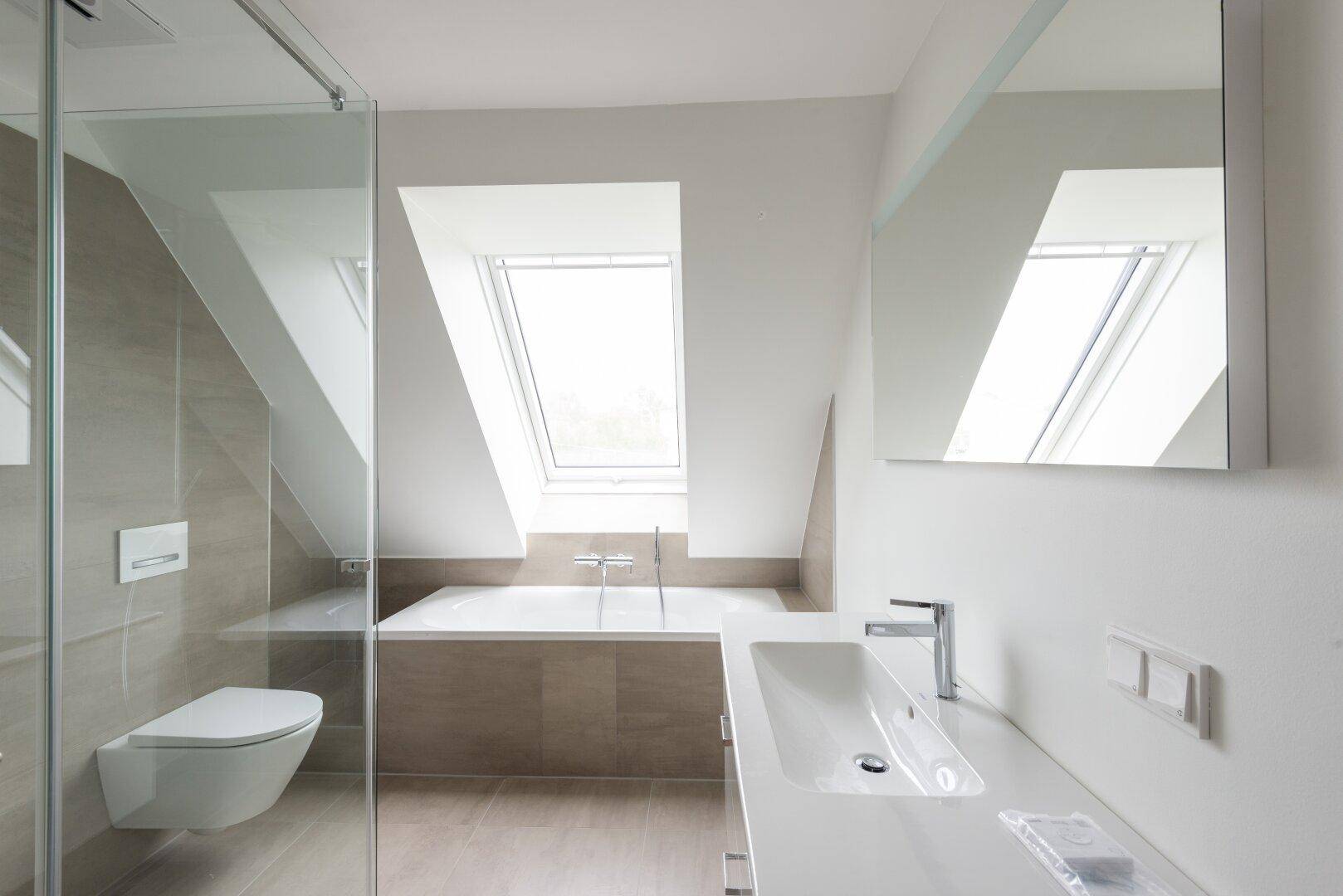 Modernes Badezimmer mit Badewanne unter einem Dachfenster, Wand-WC und eleganten Fliesen.