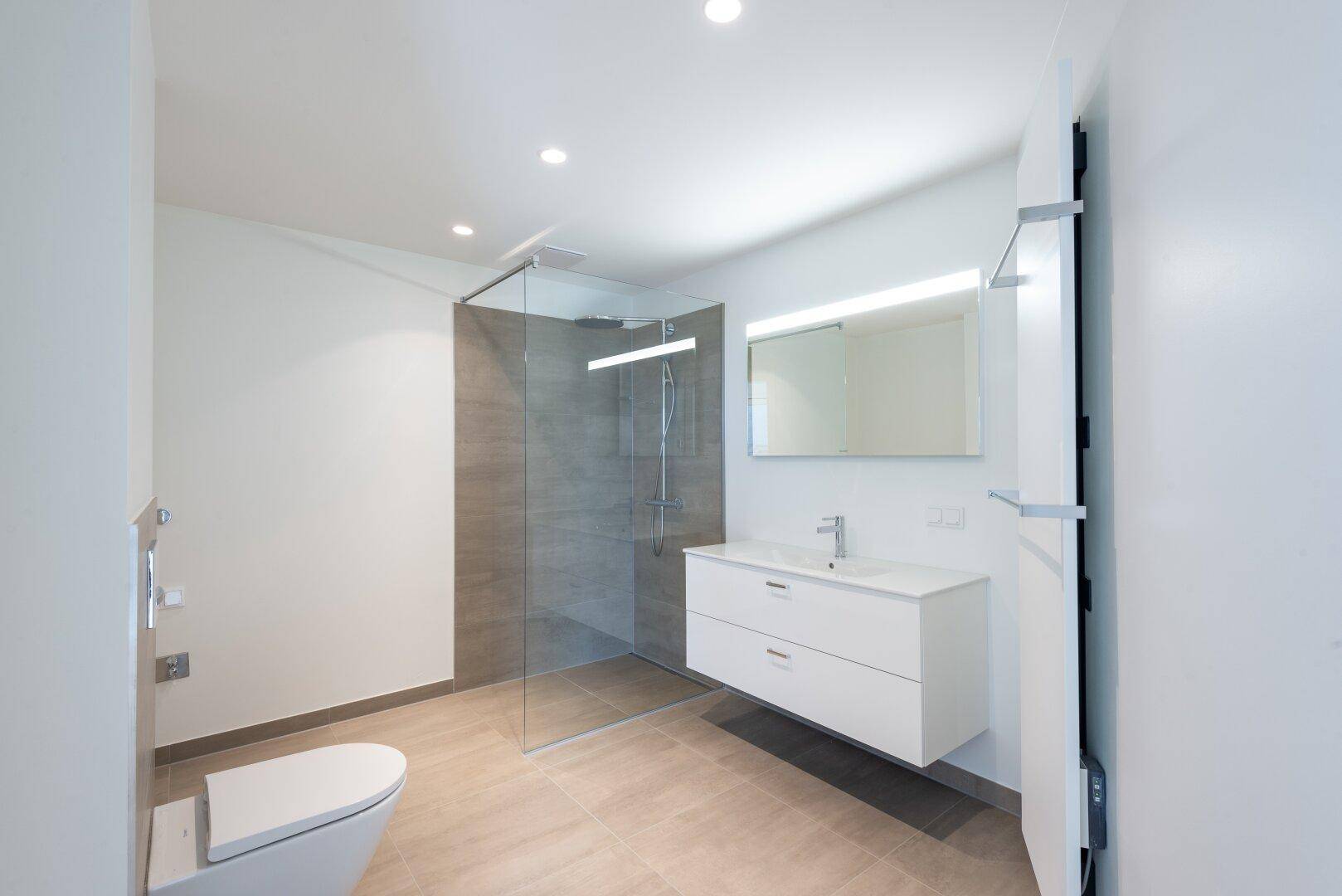 Helles, modernes Badezimmer mit begehbarer Dusche, wandhängendem WC und elegantem Waschtisch.