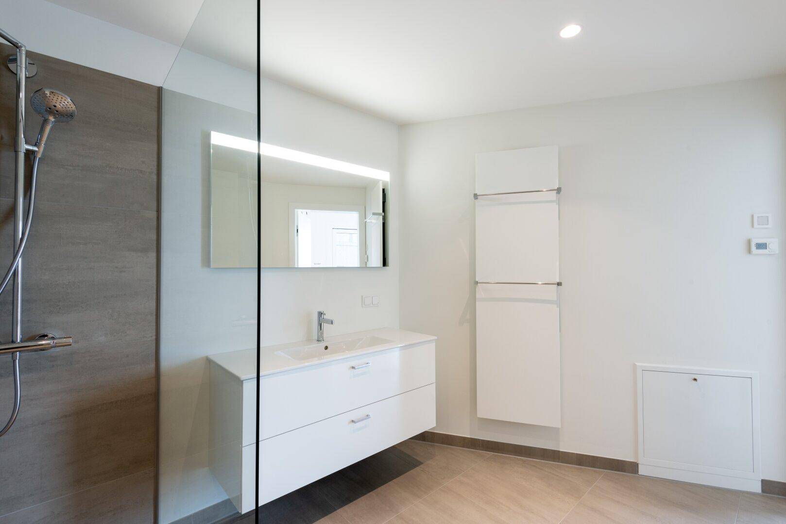 Modernes Badezimmer mit begehbarer Dusche, schwebendem Waschtisch und beheiztem Handtuchhalter.