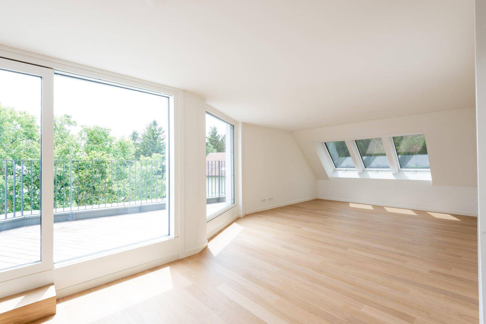 Heller Wohnraum mit großen Fenstern, Dachfenstern und hellem Holzparkettboden.