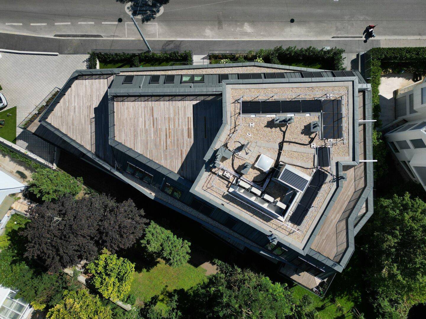 Weitläufige Dachterrasse mit Holzbelag und moderner Lounge-Möblierung, umgeben von Bäumen.