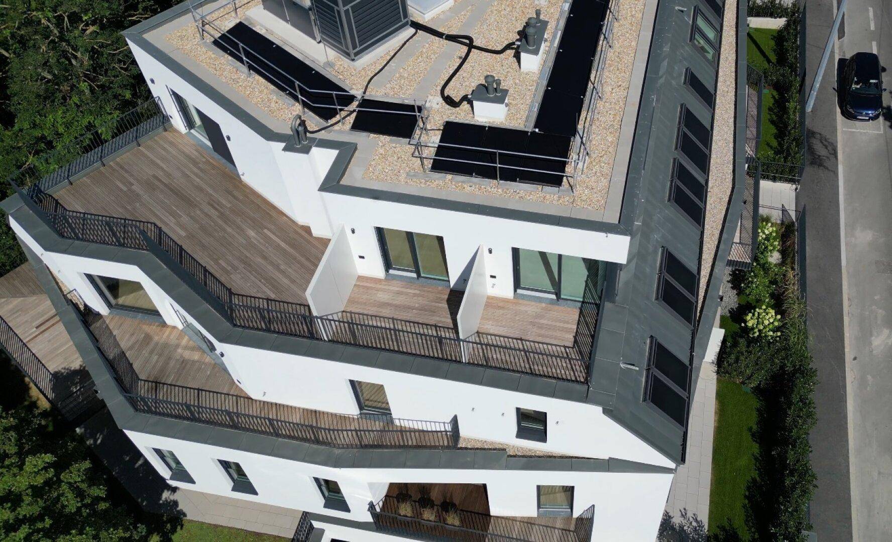 Mehrere Balkone und Terrassen mit schwarzen Geländern an der modernen weißen Gebäudefassade.