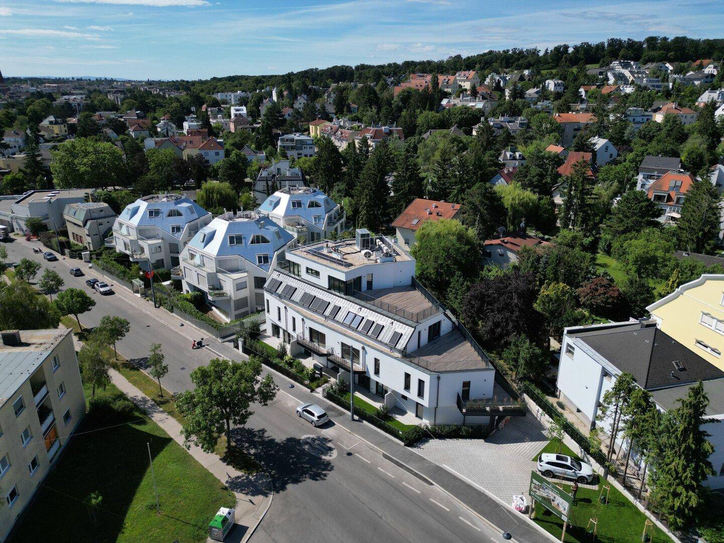 Luftaufnahme der modernen Wohnanlage in einer grünen Vorstadtumgebung mit weiteren Häusern.