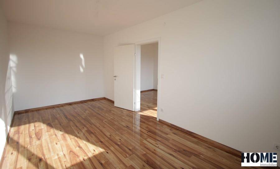 Lichtdurchfluteter Raum mit Holzboden und weiß gestrichenen Wänden.