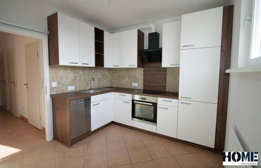 Moderne Einbauküche mit weißen und holzfarbenen Schränken, ausgestattet mit Geräten.