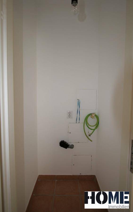 Kleiner Hauswirtschaftsraum mit Anschlüssen für Waschmaschine und Terrakotta-Fliesenboden.