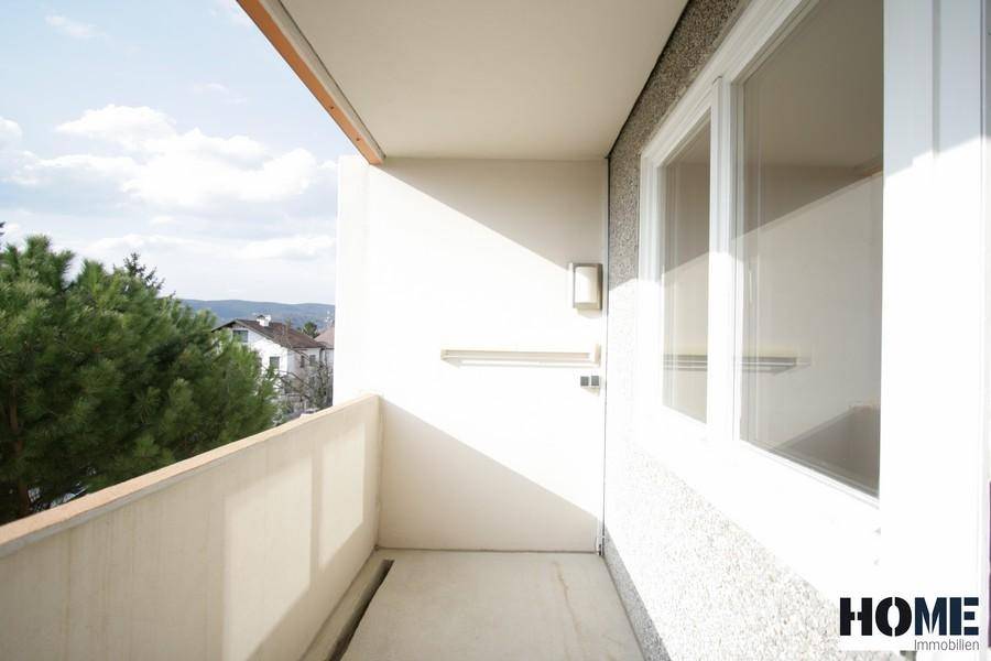 Schmaler Balkon mit heller Wand und weitem Blick in die Ferne.