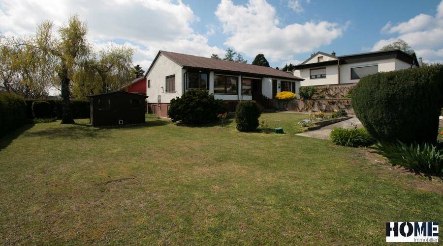 Weitläufiger Garten mit Rasenfläche, Gartenhaus und dem Einfamilienhaus.