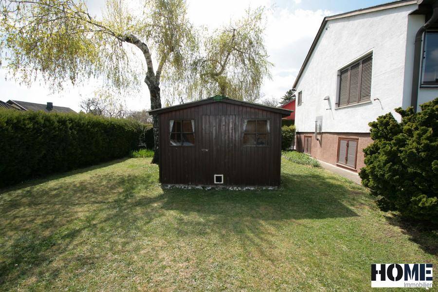 Kleines Gartenhaus aus Holz auf der Rasenfläche im Garten.