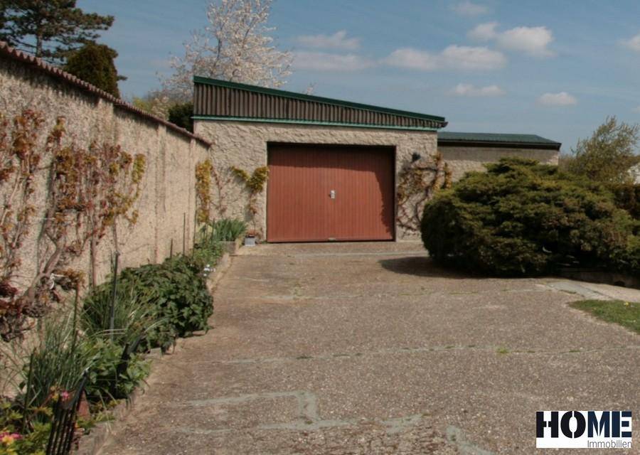 Garage mit braunem Tor und gepflasterter Einfahrt.