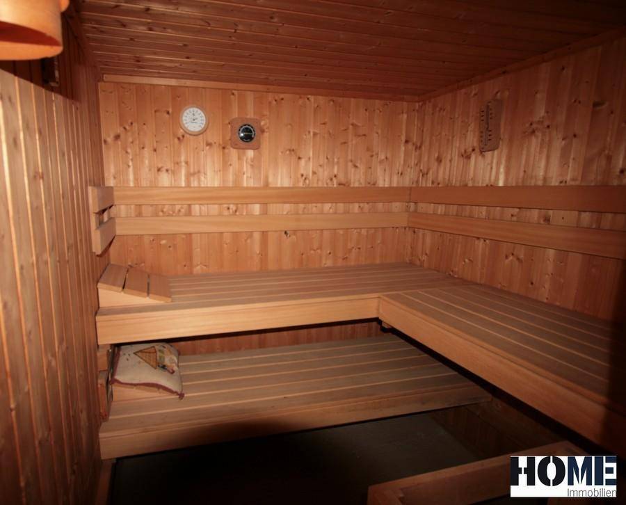 Gemütliche Holzsauna mit mehreren Bänken und integriertem Thermometer für Entspannung.