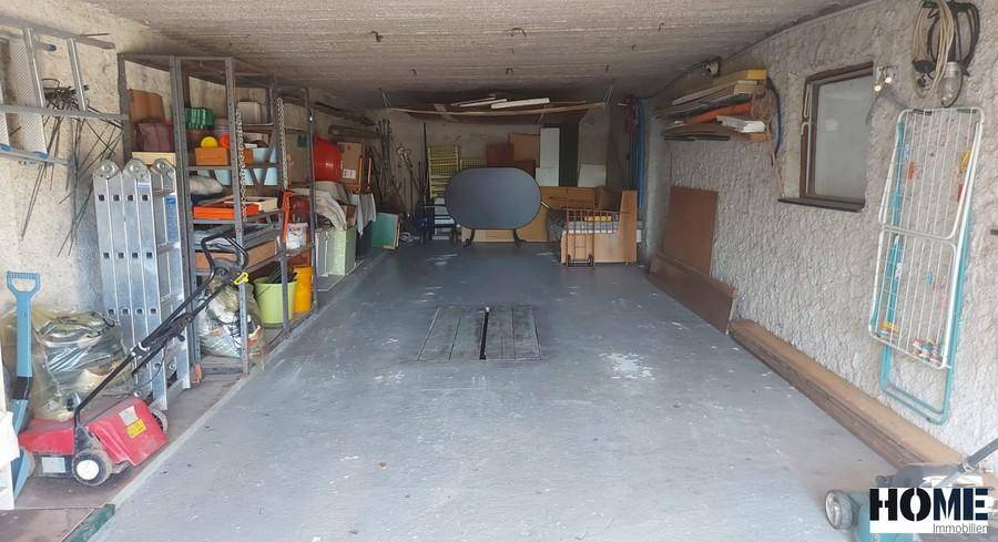 Geräumige Garage mit Betonboden, Grube und viel Stauraum für Werkzeuge und Geräte.