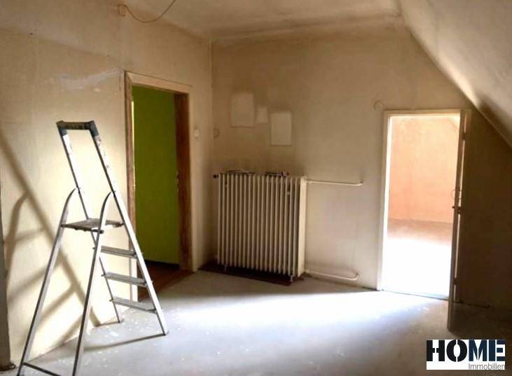 Renovierungsbedürftiger Raum im Dachgeschoss mit Heizkörper und einer Leiter, bereit für die Neugestaltung.