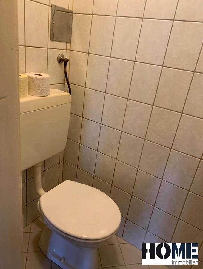 Separate Toilette mit weißen Fliesen und einem Standard-WC, in einem gepflegten und funktionalen Zustand.