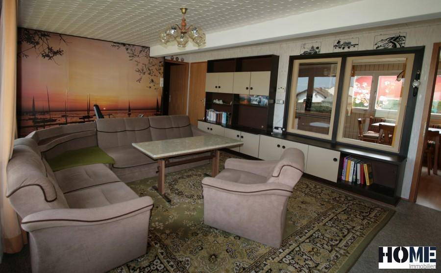 Wohnzimmer mit bequemer Sitzecke, Teppichboden und einer großen Schrankwand.