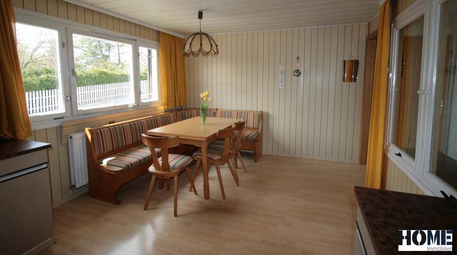 Geräumiger Essbereich in der Küche mit Holzbank, Tisch und großen Fenstern.