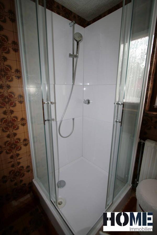 Moderne Duschkabine im Badezimmer mit klaren Glaswänden und Duschkopf.